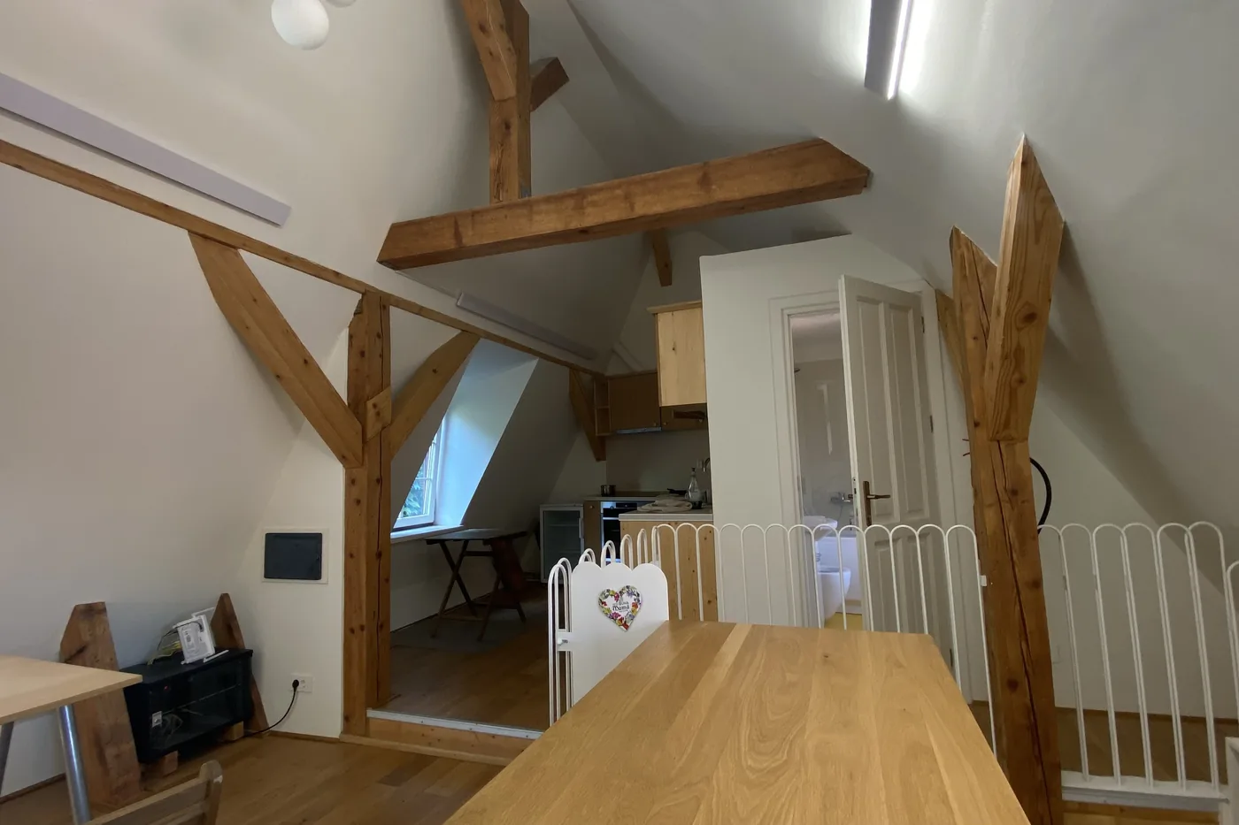 The dining table of apartment 9, with the gallery railing and the kitchen behind
