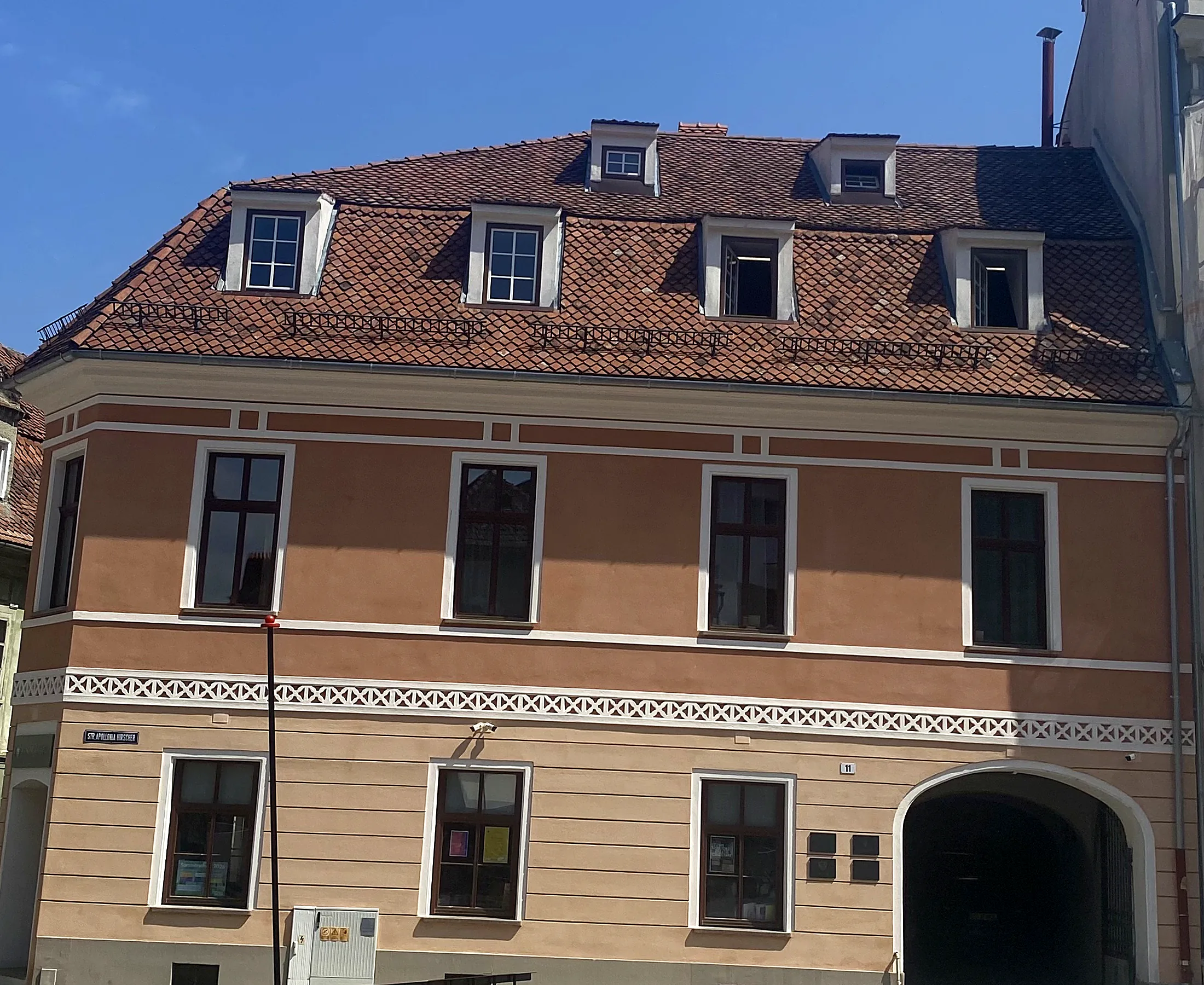 The façade of Hirscher 11 on Piața Hirscher: two storeys, the rebuilt Baroque roof with its dormers, and the carriage gate into the courtyard